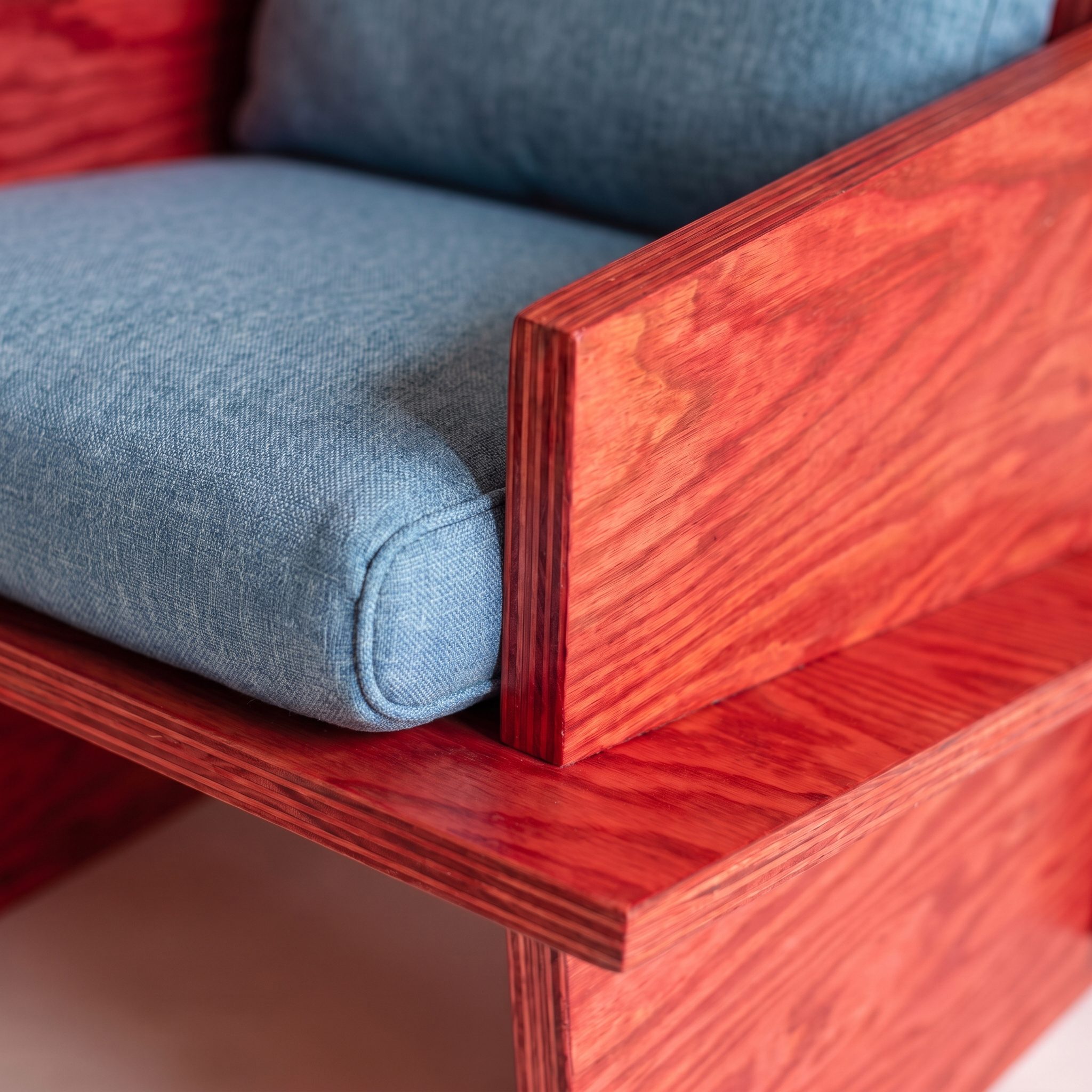 Close-up of a blue cushion with piping in the red plywood frame